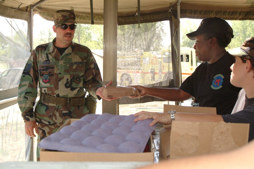 Tech. Sgt. Troy Greene, 442nd Mission Support Filght,  accepts a Meal-Ready-to-Eat from Tech. Sgt. Chantay  Thomas, 442nd Services Flight, during an exercise at Whiteman AFB. (Photo by Master Sgt. Bill Huntington)