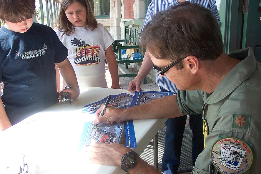 Maj. John Rogler, a 303rd Fighter Squadron A-10 Thunderbolt II pilot, signs autographs at a community event at the Katy Depot in Sedalia, Mo. The 303rd FS is part of the Air Force Reserve's 442nd Fighter Wing, based at Whiteman Air Force Base, Mo. (US Air Force photo)