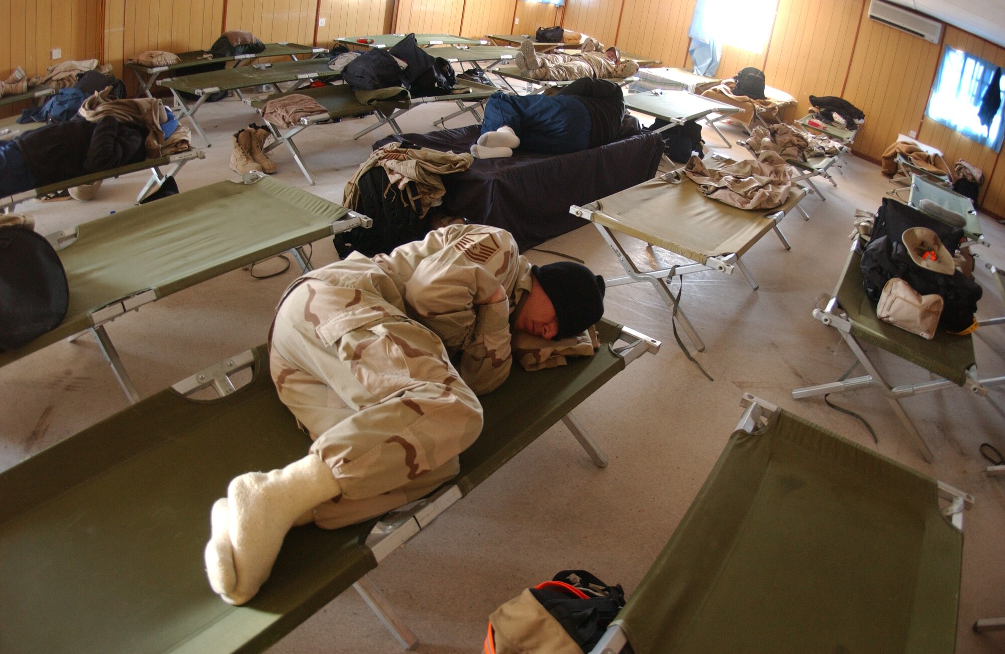 Servicemembers try to catch some sleep on cots set up in the Freedom Dining Facility while waiting for flights to move them downrange.  More than 3,000 transients spent the night on base Jan. 18.  (Air Force photo by Staff Sgt. Joshua Strang)
