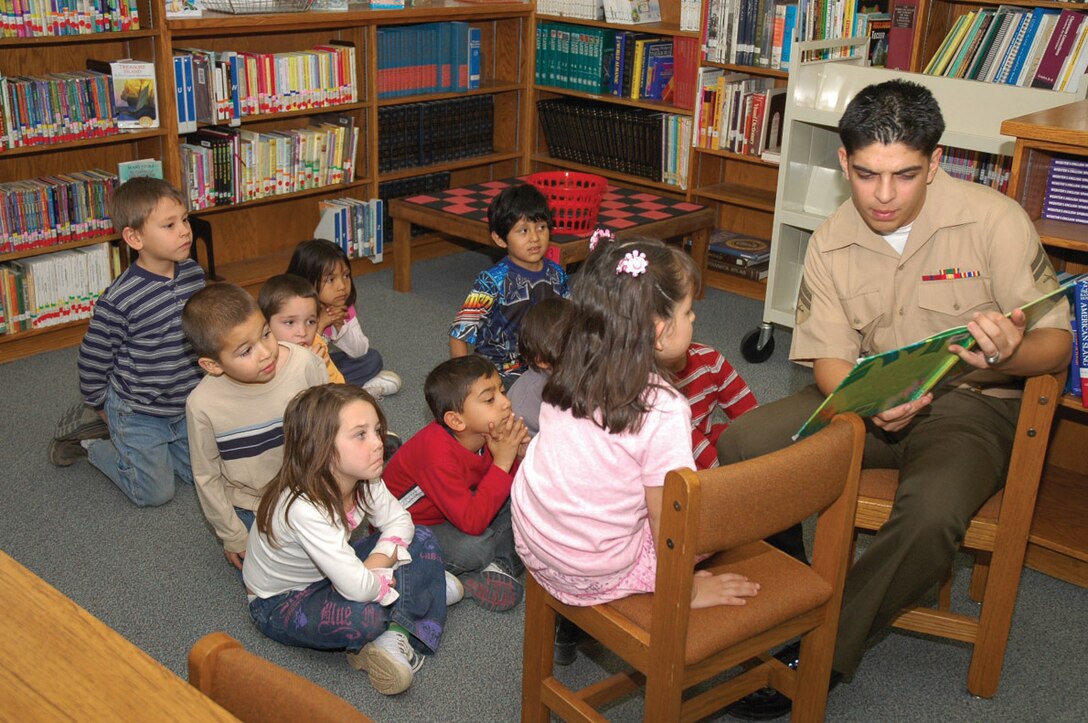 Cpl. Ralph Garcia, MAG-13, Consolidated Personnel Administration Center separations clerk, reads to a kindergarten class during their library time as a part of the Partnership for Education program Jan. 24 at the Gwyneth Ham Elementary School. Station Marines from five different squadrons have a school designated to them and will visit them once a month.
