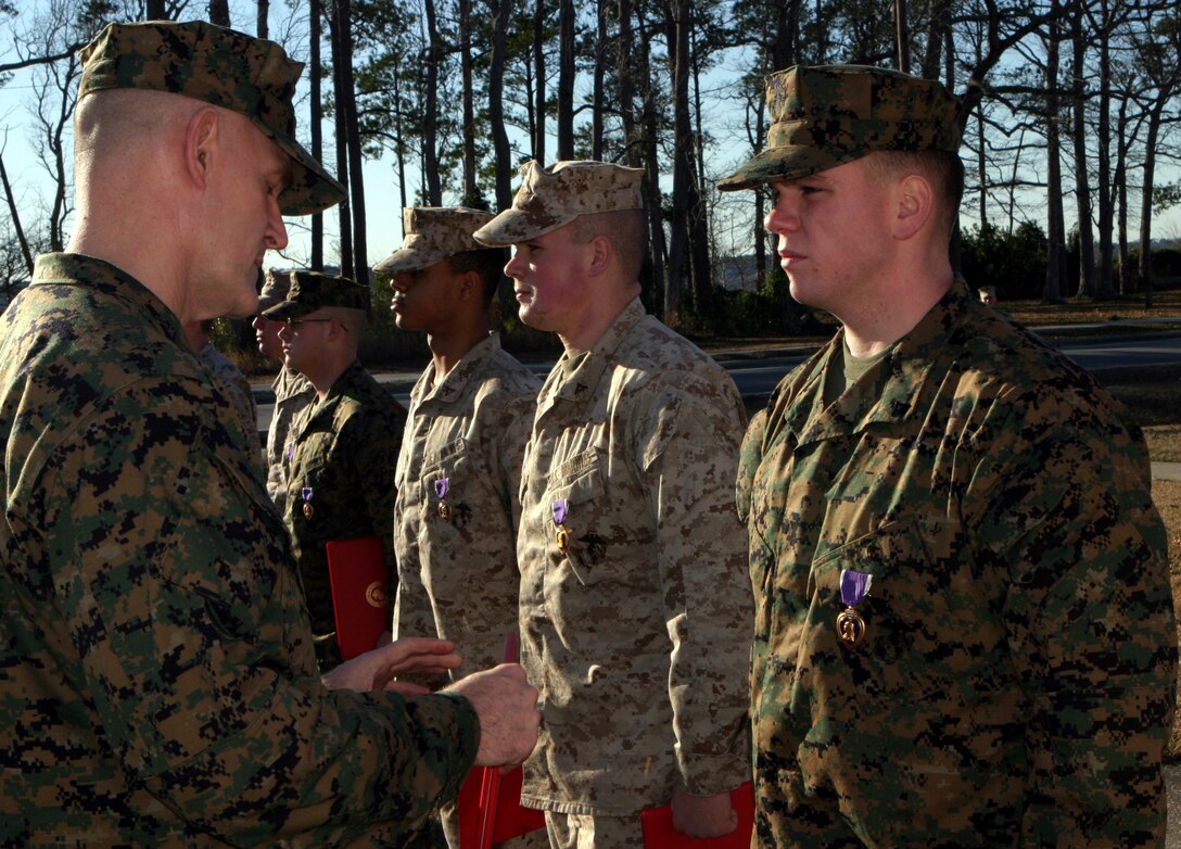 MARINE CORPS BASE CAMP LEJEUNE, N.C. - Marines with the 2nd Marine Regiment stand at attention as Col. George P. Garrett, 2nd Marine Division's chief of staff, presents them their Purple Heart Medals here Jan. 25.  Eight of the regiment's Marines were awarded these medals for injuries suffered during a recent deployment to Iraq, while another leatherneck was presented a Navy Achievement Medal with combat distinguishing device for displaying courage under enemy fire.
