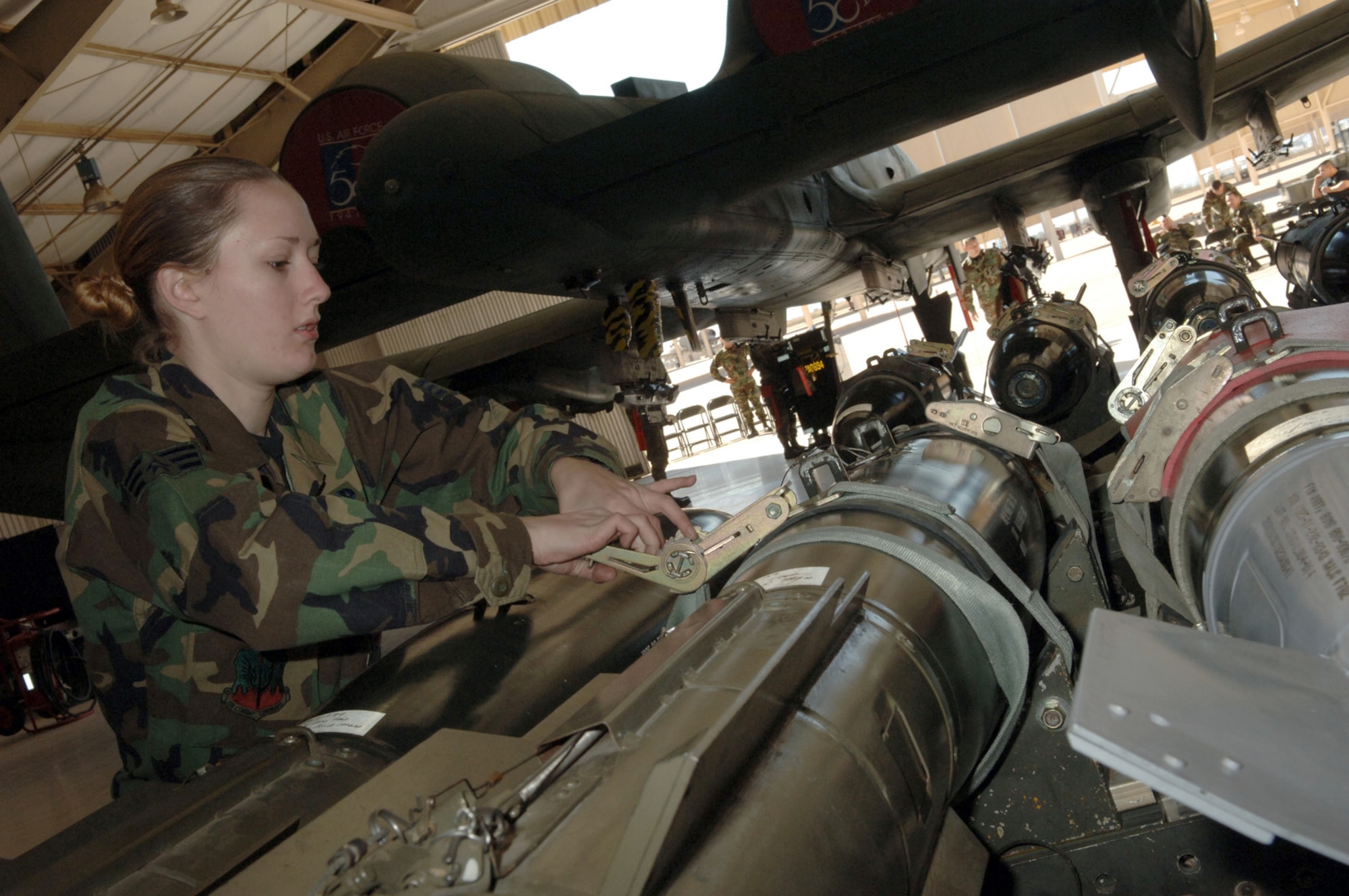 DAVIS-MONTHAN AIR FORCE BASE, Ariz. (AFPN) -- Senior Airman Jennifer Martin unstraps bombs and prepares to inspect them prior to loading on to the awaiting A-10 Thunderbolt as part of a load crew competition here.  Airman Martin is assigned to the 355th Aircraft Maintenance Squadron, which is comprised of the 354th, 357th and 358th Aircraft Maintenance Units. The 357th AMU placed first and completed the load in 38 minutes and 44 seconds. (U.S. Air Force photo by Staff Sgt. Lanie McNeal)
