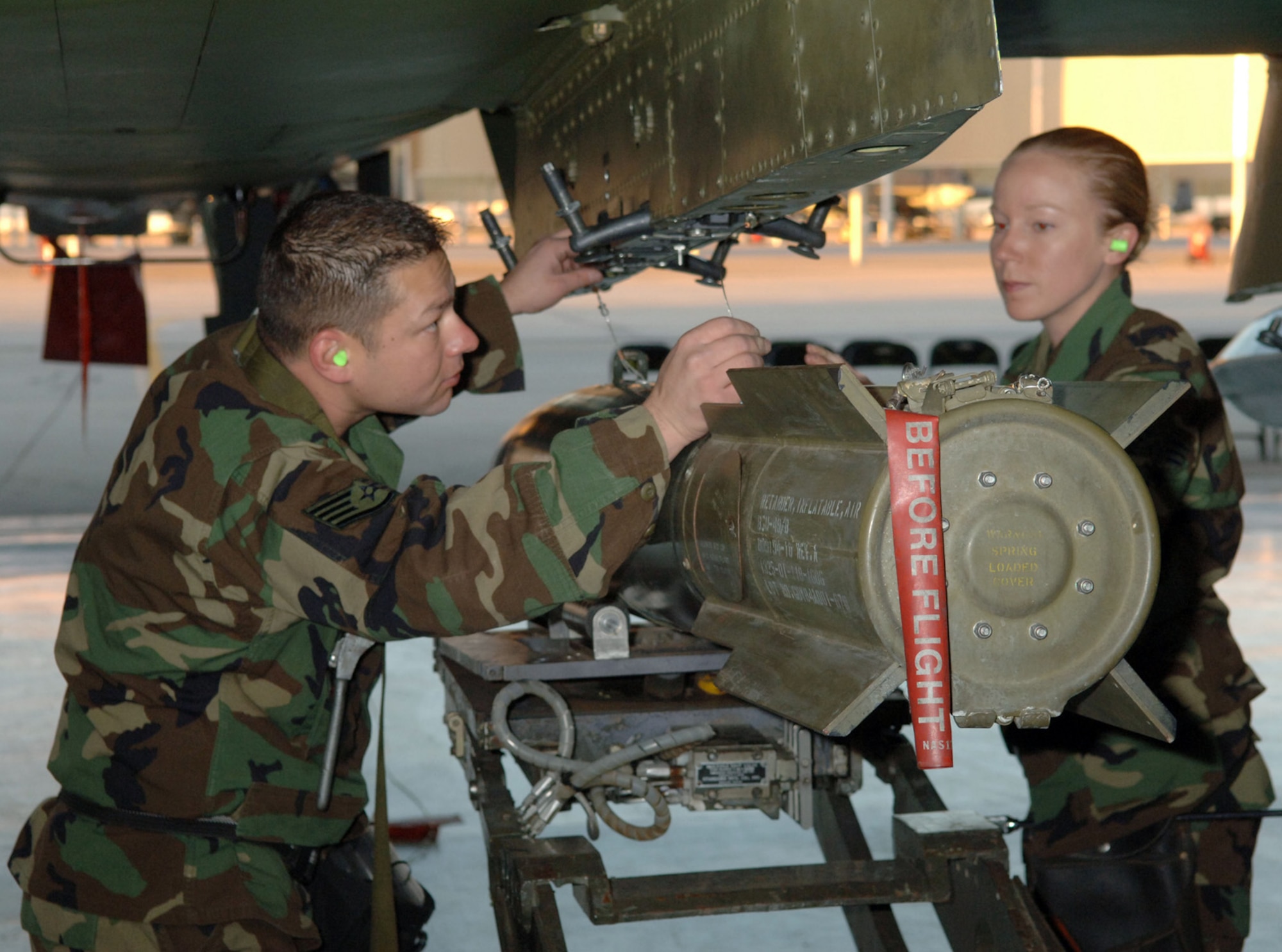 DAVIS-MONTHAN AIR FORCE BASE, Ariz. (AFPN) -- Staff Sgt. Luis Heredia and Senior Airman Jessica Steele line up the suspension lugs of the 500-pound bomb to ensure it will lock into place properly for transportation and than release at its target site.  The two Airmen are assigned to the 355th Aircraft Maintenance Squadron.  The 355th AMXS is comprised of the 354th, 357th and 358th Aircraft Maintenance Units. The 357th AMU placed first and completed the load in 38 minutes and 44 seconds.  (U.S. Air Force photo by Staff Sgt. Lanie McNeal)