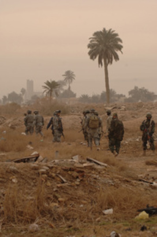 U.S. Army soldiers and Iraqi police officers walk through an empty lot as they search for weapons caches during a joint operation in the Zafaraniyah district of Baghdad, Iraq, on Jan. 23, 2006. The soldiers are assigned to the Army's 4th Battalion, 320th Field Artillery Regiment, 101st Airborne Division. 