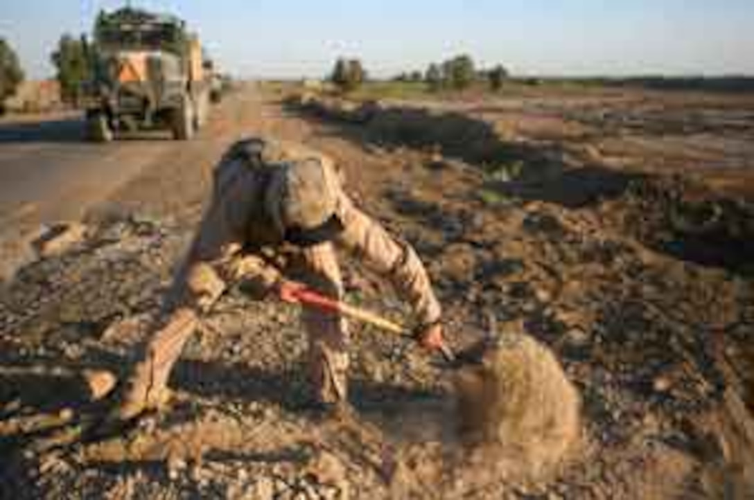 In an effort to smooth out a pot hole that was recently filled, Sgt. Shawn Peterson, a 27-year-old native of Missoula, Mont., shovels dirt during a route repair mission May 25, 2006. The threat of improvised explosive devices is one of the main reasons the Marines conduct route repairs. Not only are they a hazard to military convoys, but the craters created when an IED explodes provides insurgents with a hiding spot to place future devices. The roads Charlie Company, commonly referred to as ?Hell-Bent Charlie? and part of Combat Logistics Battalion 5 based at Camp Fallujah, work on are often traveled by Iraqi citizens, but are also used by American service members and Iraqi Security Forces.