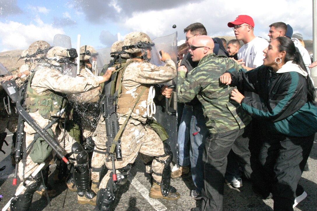 Marines from the 11th Marine Expeditionary Unit, Battalion Landing Team 1st Battalion, 4th Marine Regiment, based out of Camp Pendleton, push a crowd of unruly protesters during a consulate security training exercise during Joint Task Force Exercise 06, Jan. 13-25 aboard the U.S.S. Peleliu and throughout Camp Pendleton.