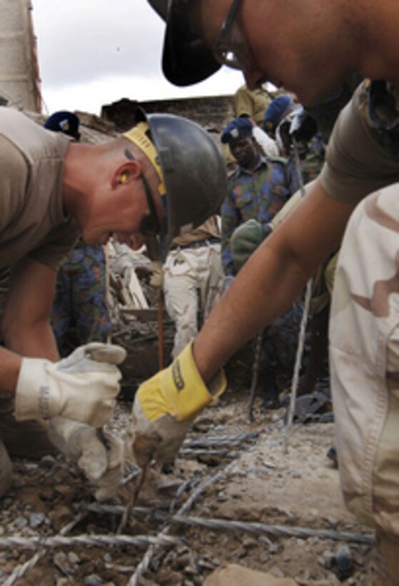 U.S. Navy Seabee Petty Officers 3rd Class Robert Modine (left) and Jason Blanchard (right) work to expose reinforcing rods as they help in the rescue and recovery efforts in a collapsed building in Nairobi, Kenya, on Jan. 25, 2006. The collapse of the building on January 23 has killed several people and injured others. The Seabees came to aid in the rescue from their forward-deployed site at Camp Lemonier, Djibouti. 