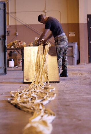 NELLIS AIR FORCE BASE, Nev. (AFPN) -- Senior Airman Daniel Desfassiaux inspects and repacks an F-117A Nighthawk deceleration parachute Jan. 25 during Red Flag 06-1 here Jan. 21 to Feb. 18.  Red Flag tests fliers' war-fighting skills in realistic combat situations. Flights involve more than 80 aircraft, including B-2 Spirit bombers and F-16 Fighting Falcons. The aircraft will fly missions day and night at the nearby Nevada Test and Training Range.   Along with the Air Force, units are participating from the Army, Navy, Marine Corps, United Kingdom and Australia. Airman Desfassiaux is a survival equipment journeyman with the 9th Fighter Squadron at Holloman Air Force Base, N.M. (U.S. Air Force photo by Master Sgt. Kevin J. Gruenwald)