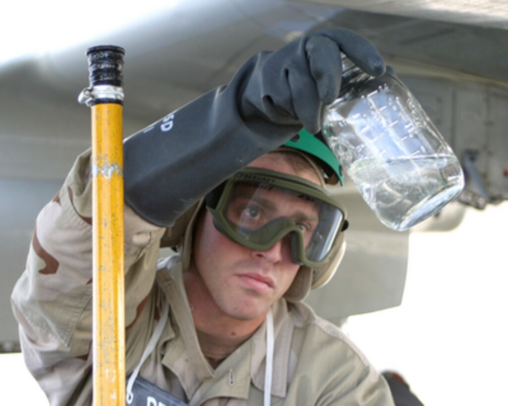 U.S. Navy Petty Officer 2nd Class Graham Keithley looks at fuel drawn from a P-3C Orion aircraft checking for contaminants before a flight on Jan. 25, 2006. Keithley is a Navy aviation maintenance administrationman assigned to Patrol Squadron 47 on deployment to Qatar. 