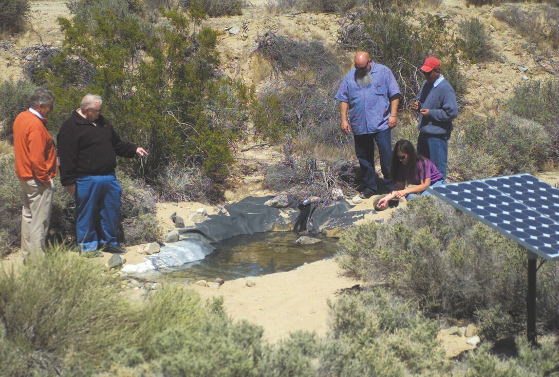 Base Environmental Division employees monitor progress of the Solar Powered Water Hole Pilot Project and its impact in the area April 18. Several things must be monitored daily such as water temperature, wind direction and the equipment must be checked for proper working condition.