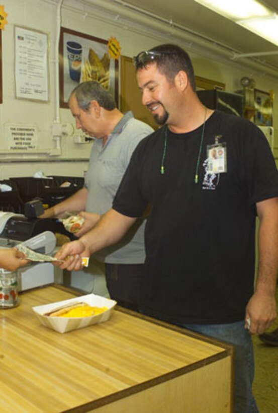 Raul Lara, heavy mobile equipment mechanic for Cost Work Center 723, purchases a hot dog and cheese fries from the Lanzer?s Lounge.