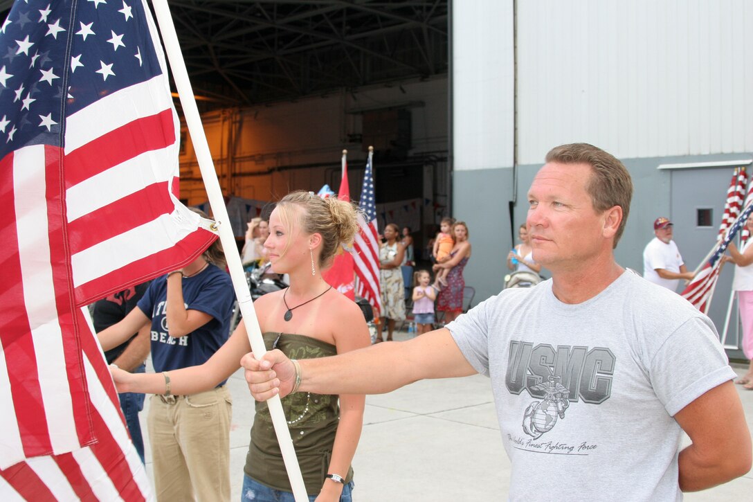Jack Ford displays the national ensign while waiting to reuntie with his son, Lance Cpl. Cody J. Ford, July 28. Lance Cpl. Ford was deployed with Marine Tactical Electronic Warfare Squadron 2 in Al Asad, Iraq.