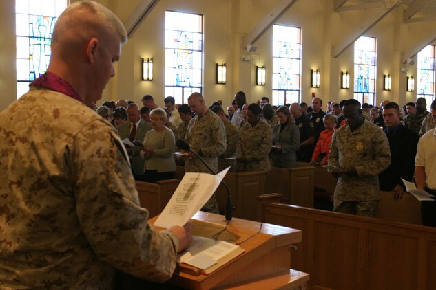 060127-M-7082F-004 CAMP PENDLETON, Calif. -- Navy Lt. Cmdr. Greg T. Schluter leads all who have come to pay their respects to Sgt. Adam Cann at his memorial service here Jan. 27 in prayer. Cann, from Destin, Fla., was killed in action Jan. 5 while conducting crowd control with his dog Bruno during his second deployment to Iraq. Schluter is the Security Battalion Chaplain. (Official U.S. Marine Corps photo by Lance Cpl. Patrick J. Floto)(released)
