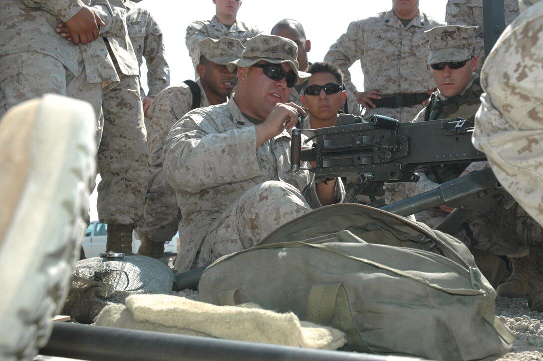 Staff Sgt. David Ramirez, Marine Wing support Squadron 371 production chief, shows Marines the correct way to sit while firing the M2 .50-caliber machine gun at the Yuma Proving Ground's Grave Range on June 29. The Marines have been training at the range for their February development to Iraq.