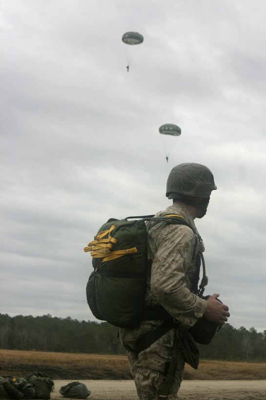MARINE CORPS BASE CAMP LEJEUNE, N.C. - A Marine with 2nd Reconnaissance Battalion observes as fellow Marines land onto Drop Zone Plover here Jan. 30 after parachuting out of a helicopter.  Several of the battalion's Marines and sailors practiced jumping out of a helicopter while wearing the SF10-A parachute, a model that replaced the older MT11 and features superior maneuverability along with a slower rate of descent.