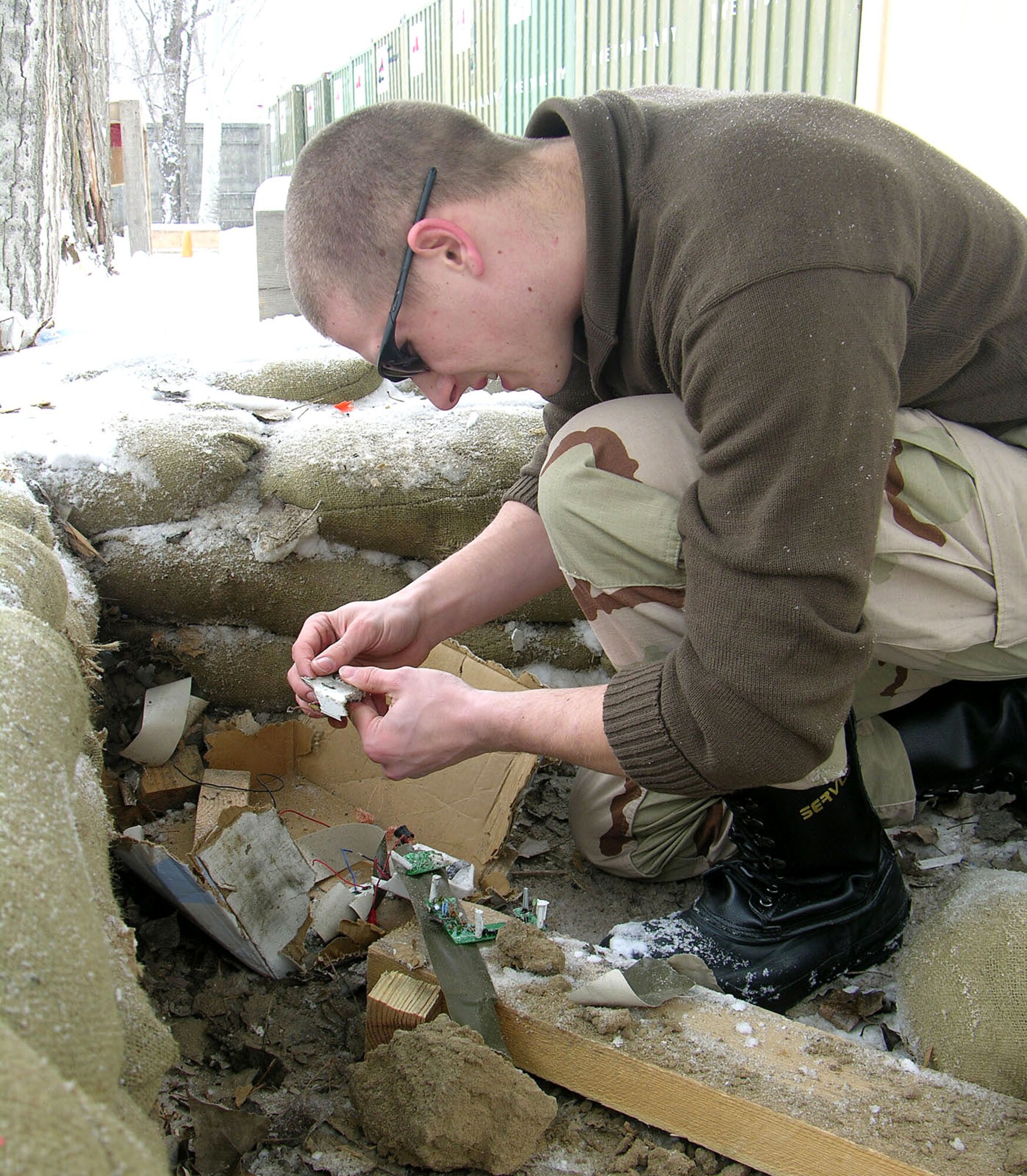 MANAS AIR BASE, Kyrgyzstan (AFPN) -- Senior Airman Robin Cunningham sifts through the remains of a mock improvised explosive device destroyed during explosive tool training here.  Airman Cunningham is an explosive ordnance technician with the 376th Expeditionary Civil Engineer Squadron, Explosive Ordnance Disposal flight. He is deployed from Whiteman Air Force Base, Mo. (U.S. Air Force photo by Capt. James Bressendorff)
