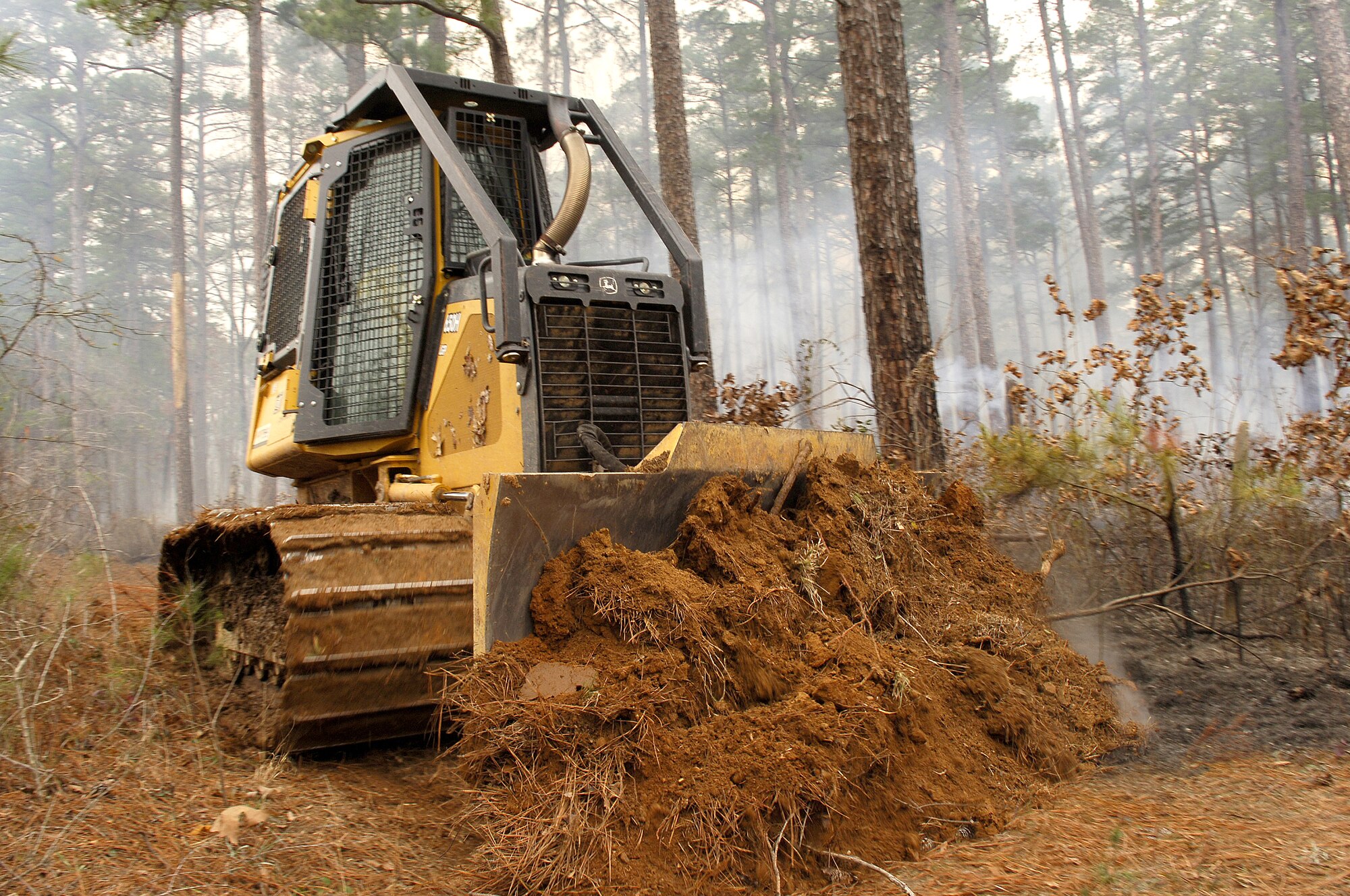 BARKSDALE AFB, La. (AFPN) -- Phillip Bell drives a bulldozer to create a fire break to help contain controlled burning. The 200-acre burn Jan. 26 was a timber stand improvement burn, and is one of 10 scheduled controlled burns on Barksdale's East Reservation this year. The burning is conducted to reduce overall fire fuel on the ground, which in turn helps prevent forrest fires. Mr. Bell is a wildlife technician here. (U.S. Air Force photo by Senior Airman Stephen J. Otero)
