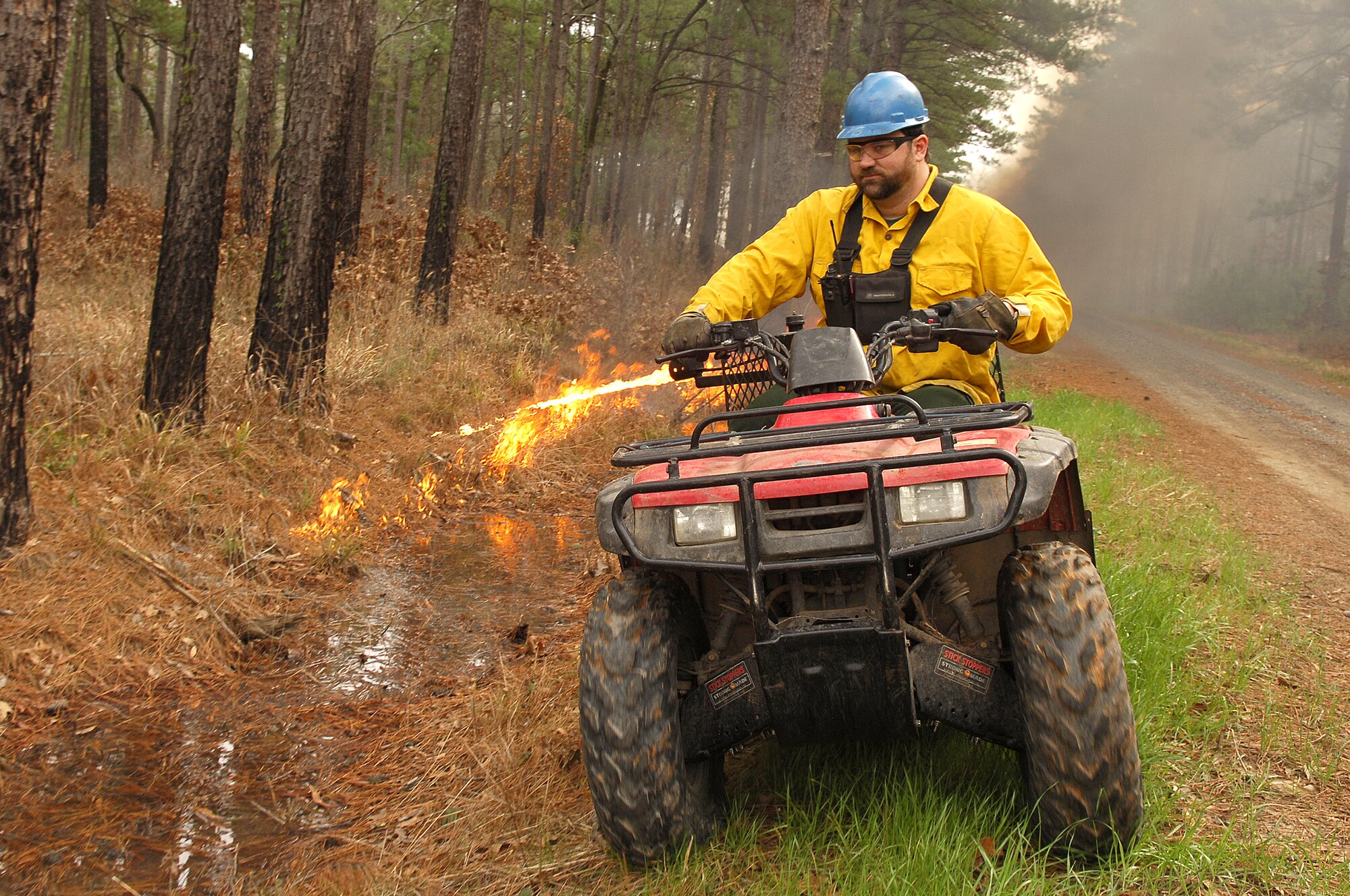 BARKSDALE AFB, La. (AFPN) -- Mark Gates performs a perimeter burn using a terra torch mounted to the rear of an all-terrain vehicle. The 200-acre burn Jan. 26 was a timber stand improvement burn, and is one of 10 scheduled controlled burns on Barksdale's East Reservation this year. The burning is conducted to reduce overall fire fuel on the ground, which in turn helps prevent forest fires. Mr. Gates is the base biologist here.  (U.S. Air Force photo by Senior Airman Stephen J. Otero)
