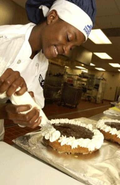 Airman 1st Class Sparkle Reid, 60th Services Squadron, puts icing on a cake. Travis Food Service facilities won the Air Mobility Command Services Hennessy Award for the fourth time since 2001.