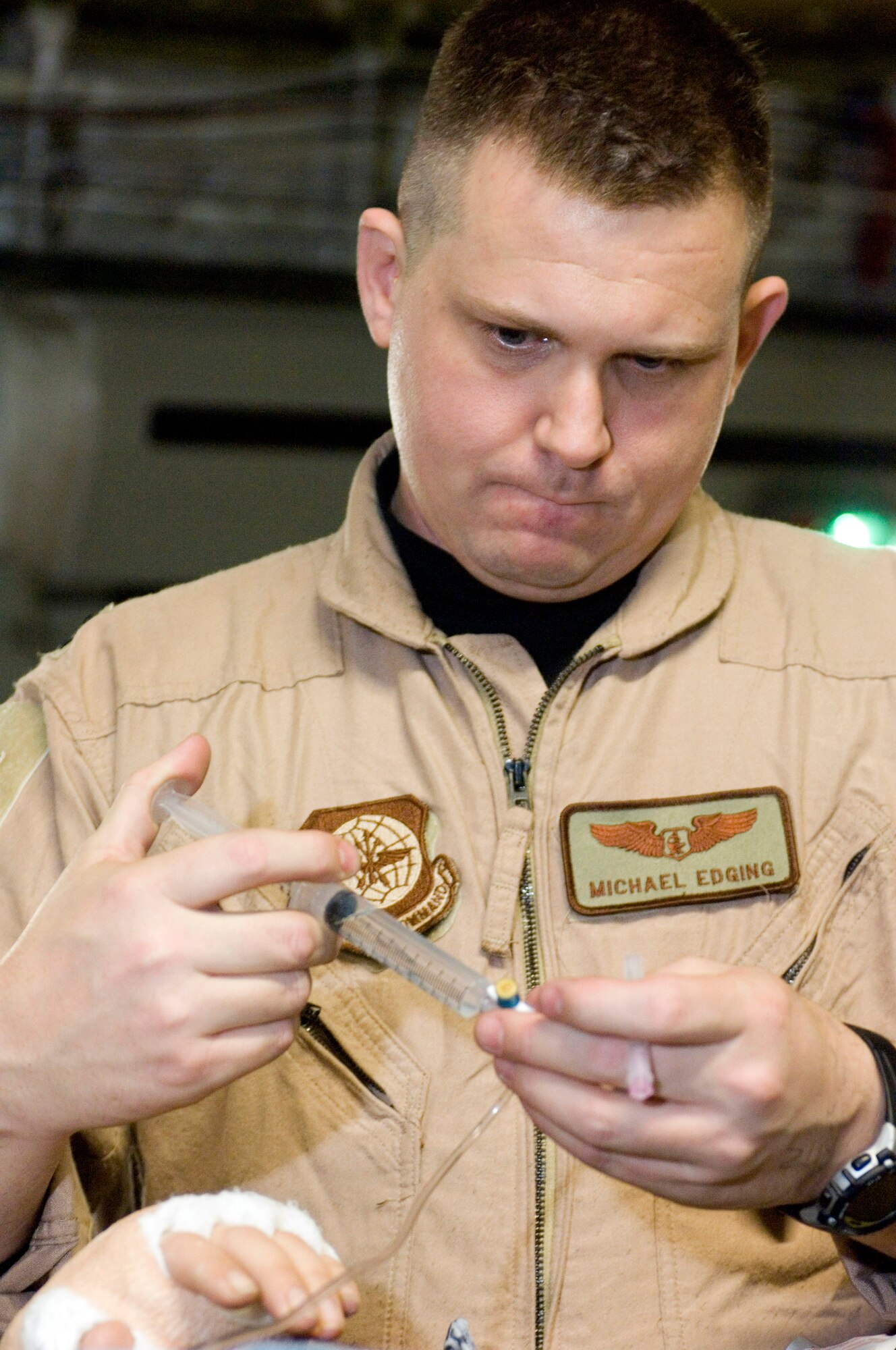 OVER IRAQ (AFPN) -- Capt. Michael Edging injects a patient's medicine while on a C-17 Globemaster III bound for Germany. Captain Edging is a flight nurse with the 791st Expeditionary Aeromedical Evacuation Squadron moving servicemembers to health-care facilities in Germany and the U.S.  He deployed from the 43rd AES at Pope Air Force Base, N.C.  (U.S. Air Force photo by Master Sgt. John E. Lasky)