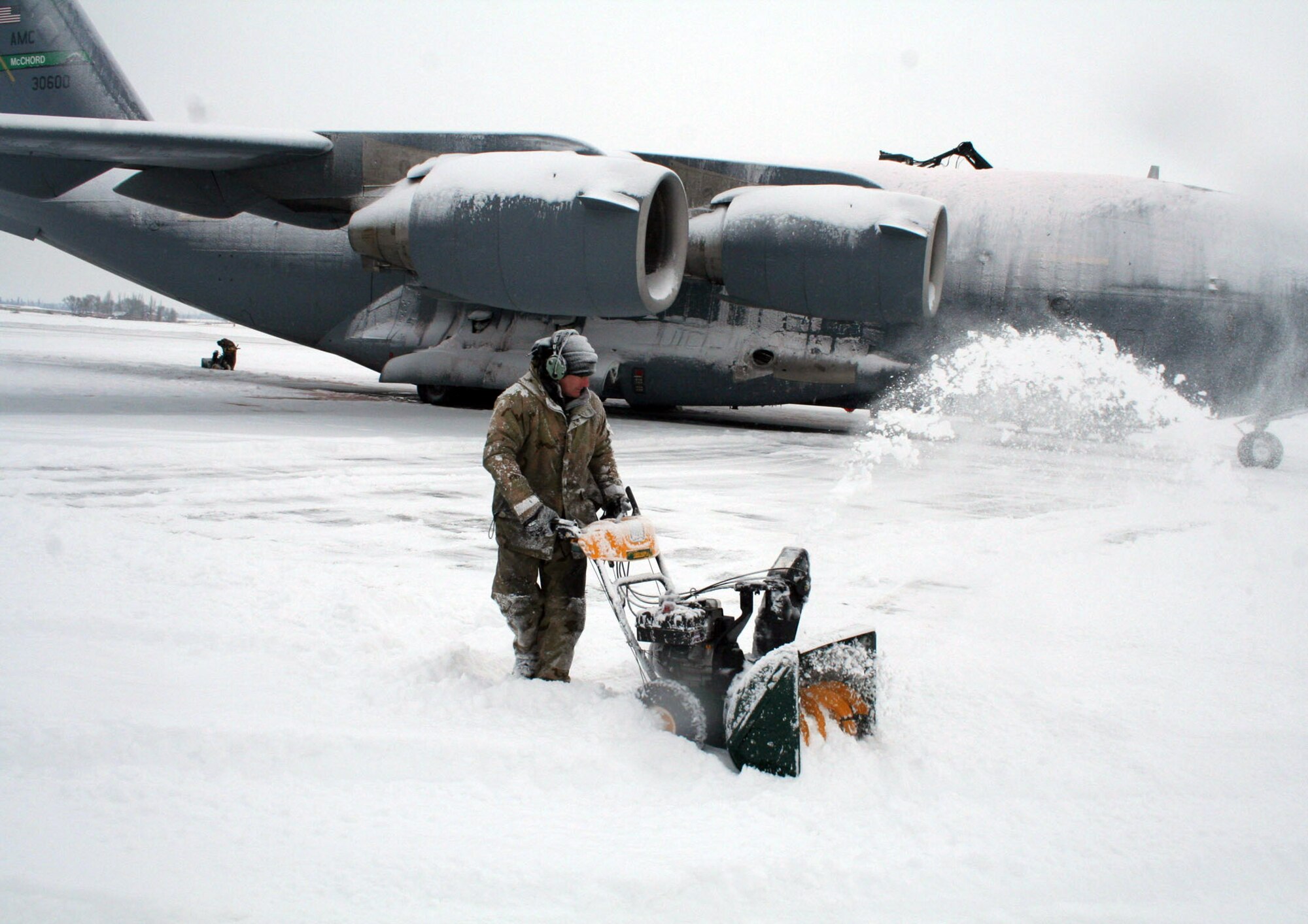 MANAS AIR BASE, Kyrgyzstan -- Airman 1st Class Michael Lepla digs out a C-17 Globemaster III Jan. 28 after 4 inches of snowfall during the night. With temperatures barely above zero and weekly snowstorms, maintainers here work nonstop to keep the aircraft and ramp clear of ice and snow. (U.S. Air Force photo by Staff Sgt. Lara Gale) 