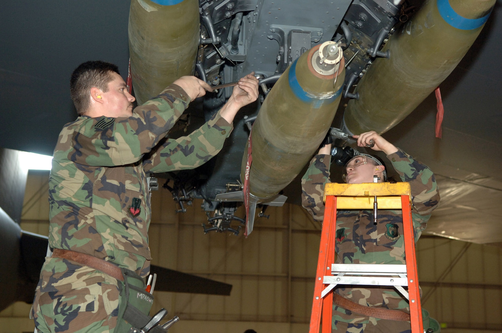MINOT AIR FORCE BASE, N.D. (AFPN) -- Tech. Sgt. Steve Root and Senior Airman Stephanie Lopez secure a bomb during a load crew competition here Jan. 27.  The crews loaded nine Mk-82 500-pound general purpose bombs during the competition. The four-person crews were graded on teamwork, safety, precision and speed.  Both Airmen are weapons loaders assigned to the 5th Aircraft Maintenance Squadron.  (U.S. Air Force photo by Airman 1st Class Christopher Boitz)
