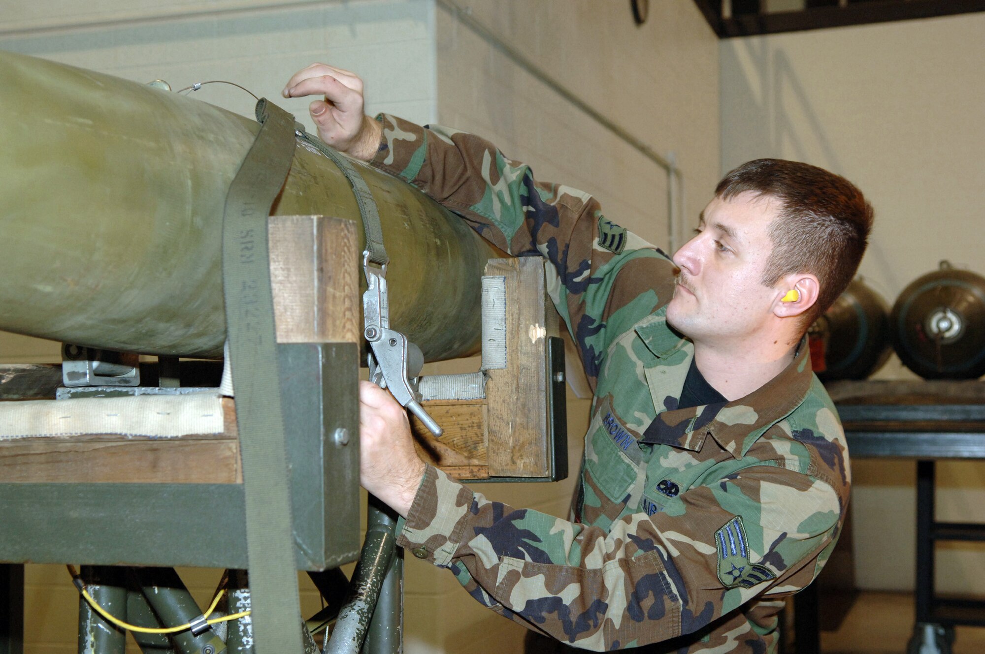 MINOT AIR FORCE BASE, N.D. (AFPN) -- Senior Airman George Brown secures a bomb onto an M-J1 jammer during a load crew competition here Jan. 27.  The crews loaded nine Mk-82 500-pound general purpose bombs onto a B-52H Stratofortress. The four-person crews were graded on teamwork, safety, precision and speed.  Airman Brown is a weapons loader assigned to the 5th Aircraft Maintenance Squadron.  (U.S. Air Force photo by Airman 1st Class Christopher Boitz)