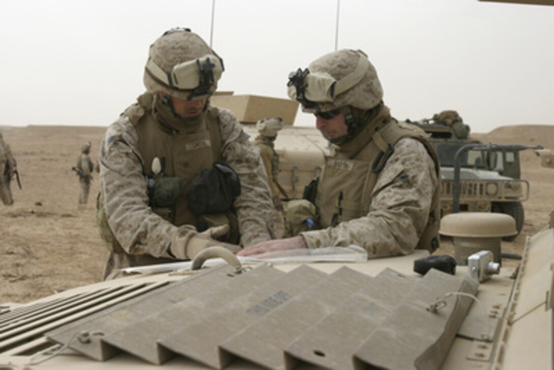 U.S. Marine Lt. Col. Drew Smith (left) and Capt. Skip Barth use the hood of a Humvee for a impromptu desk as they map out their unit's next move during operations near Hit, Iraq, on Jan. 23, 2006. Smith is the commanding officer of Battalion Landing Team, 1st Battalion, 2nd Marine Regiment. Barth is the Golf Battery commander. 