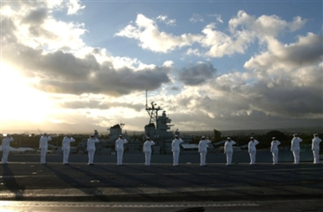 Sailors manning the rails render honors as the Nimitz-class aircraft carrier USS Ronald Reagan passes the USS Arizona Memorial in Pearl Harbor, Hawaii, June 28, 2006. The Reagan and embarked Carrier Air Wing 14 are on a regularly scheduled deployment in support of the global war on terrorism.