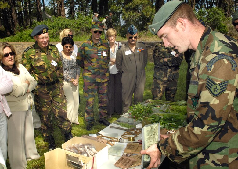 A survival, evasion, resistance and escape specialist shows the visiting attaches and their spouses the capabilities of a MREs heating element.  The group and their spouses toured a section of the SERE compound where they saw several demonstrations on the SERE mission.