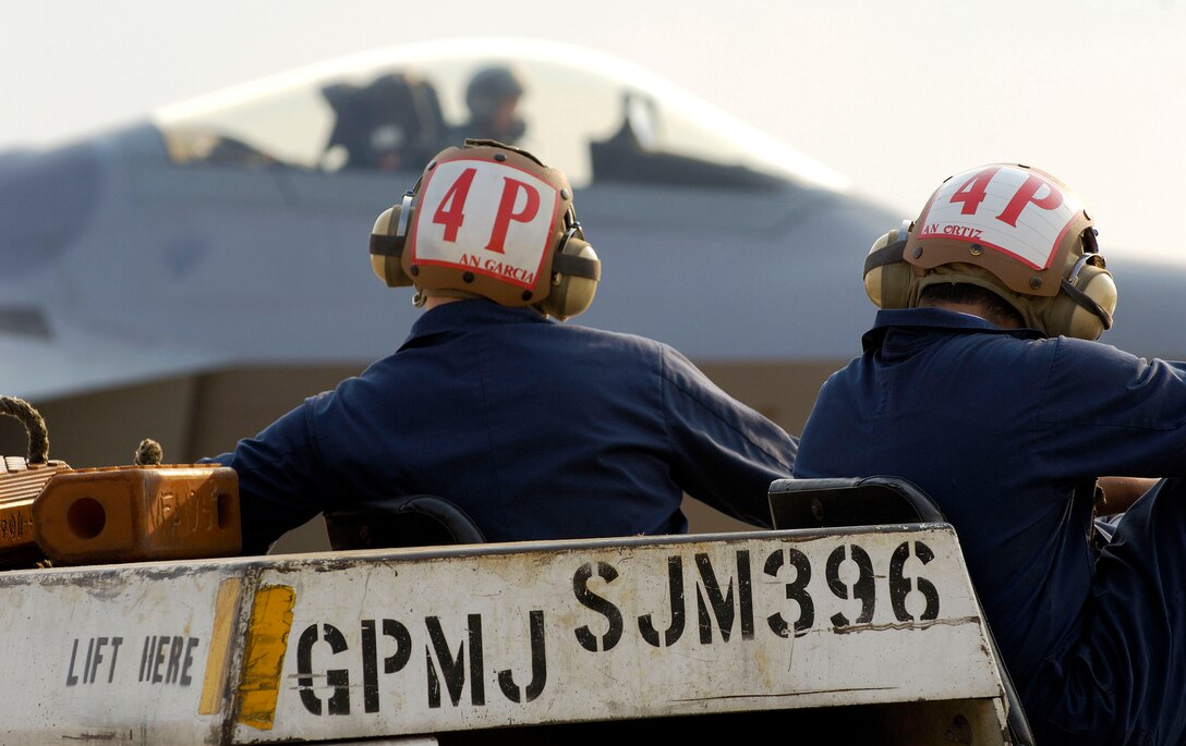 Navy F-18 Super Hornet crew chiefs assigned to Master Naval Air Base Oceana, Va., watch the arrival of F-22 Raptors from Elmendorf Air Force Base, Alaska, on Friday, June 30. The Raptors are assigned to the 27th Fighter Squadron at Langley AFB, Va. The 27th, 71st and 94th FS are flying sorties from other installations because of runway repairs at their home station. (U.S. Air Force photo/Staff Sgt. Samuel Rogers) 