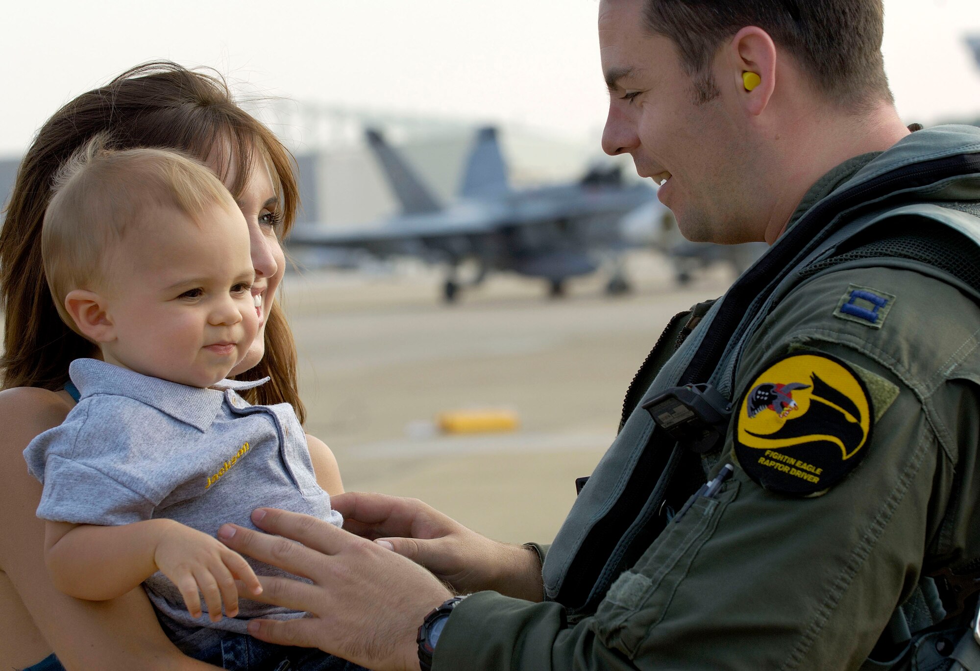 Capt. John Echols is greeted by his son, Jackson, and wife, Megan, after arriving at Naval Air Station Oceana, Va., on Friday, June 30. The 27th Fighter Squadron, along with the 71st and 94th FS from Langley Air Force Base, Va., are flying sorties from other installations because of runway repairs at their home station. Captain Echols, who just returned from Elmendorf AFB, Alaska, is an F-22 Raptor pilot assigned to the 27th FS. (U.S. Air Force photo/Staff Sgt. Samuel Rogers) 
