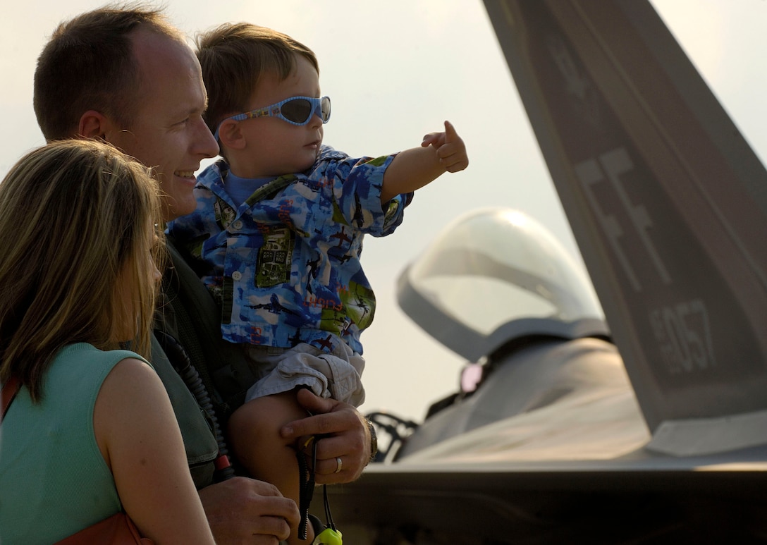 Capt. Daniel Lee shares a moment with his son, Benton, and wife, Rebecca, after arriving at Naval Air Station Oceana, Va., on Friday, June 30. The 27th Fighter Squadron, along with the 71st and 94th FS from Langley Air Force Base, Va., are flying sorties from other installations because of runway repairs at their home station. Captain Lee, who just returned from Elmendorf AFB, Alaska, is an F-22 Raptor pilot assigned to the 27th FS. (U.S. Air Force photo/Staff Sgt. Samuel Rogers)
