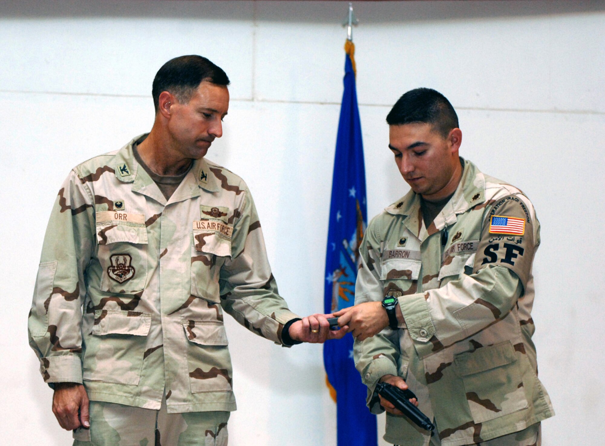 Maj. Benito Barron hands an M-9 magazine to Col. David Orr to signify the 407th Expeditionary Security Forces Squadron relinquishing the perimeter defense mission at Ali Base, Iraq, on Friday, June 30. Major Barron is the 407th ESFS commander; Colonel Orr is the 407th Expeditionary Group commander. (U.S. Air Force photo/Staff Sgt. Rasheen Douglas)