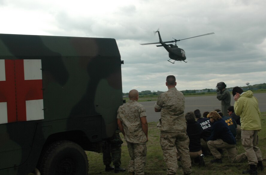 Two Marine ambulance drivers (left) and civilian medical volunteers watch a Rhode Island Army National Guard helicopter lift off from Dogpatch training area. The exercise combined the elements of military and civilian medical technicians in real-world accident scenarios. (U.S. Air Force photo/Master Sgt. Tom Allocco) 