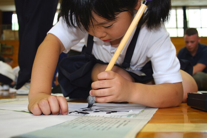 Yamamoto Ayaka, 7, Kono Elementary School 2nd grader, gracefully strokes the bristles of her brush against her paper while drawing calligraphy with Marines during their visit to her school July 5.