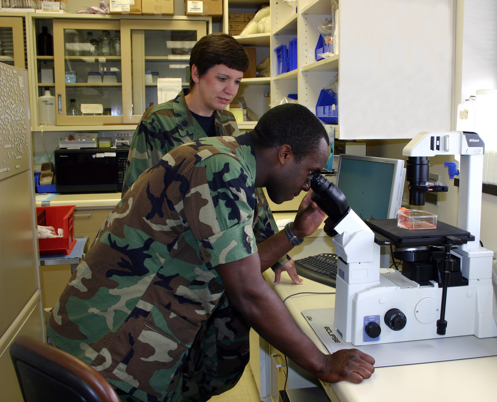 Cadet 1st Class Bryan Lawson looks at a cell culture through a microscope with Lt. Col. Marla Dejong at Wilford Hall Medical Center at Lackland Air Force Base, Texas, on Wednesday, July 5. Cadet Lawson is a student in the Cadet Summer Research Program, and is a biochemistry major at the U.S. Air Force Academy. Colonel Dejong is the 59th Clinical Research Squadron director of nursing research. (U.S. Air Force photo/2nd Lt. David Herndon)