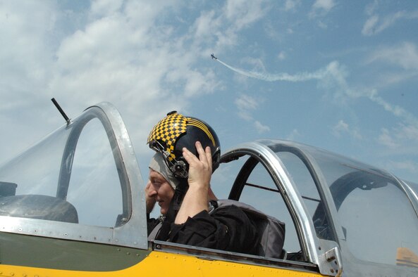 Lt. Col. Scott "Painless" Sayre, a dentist with the 445th Aerospace Medicine Squadron is seated in his Beech T-38 Mentor on the flightline at the Freedom Fest air show in Goshen, Indiana, July 1, gets ready for the Lima Lima Flight Team formation and aerobatic performance while another plane flies overhead. (U.S. Air Force Reserve Photo by Tech. Sgt. Charlie Miller)