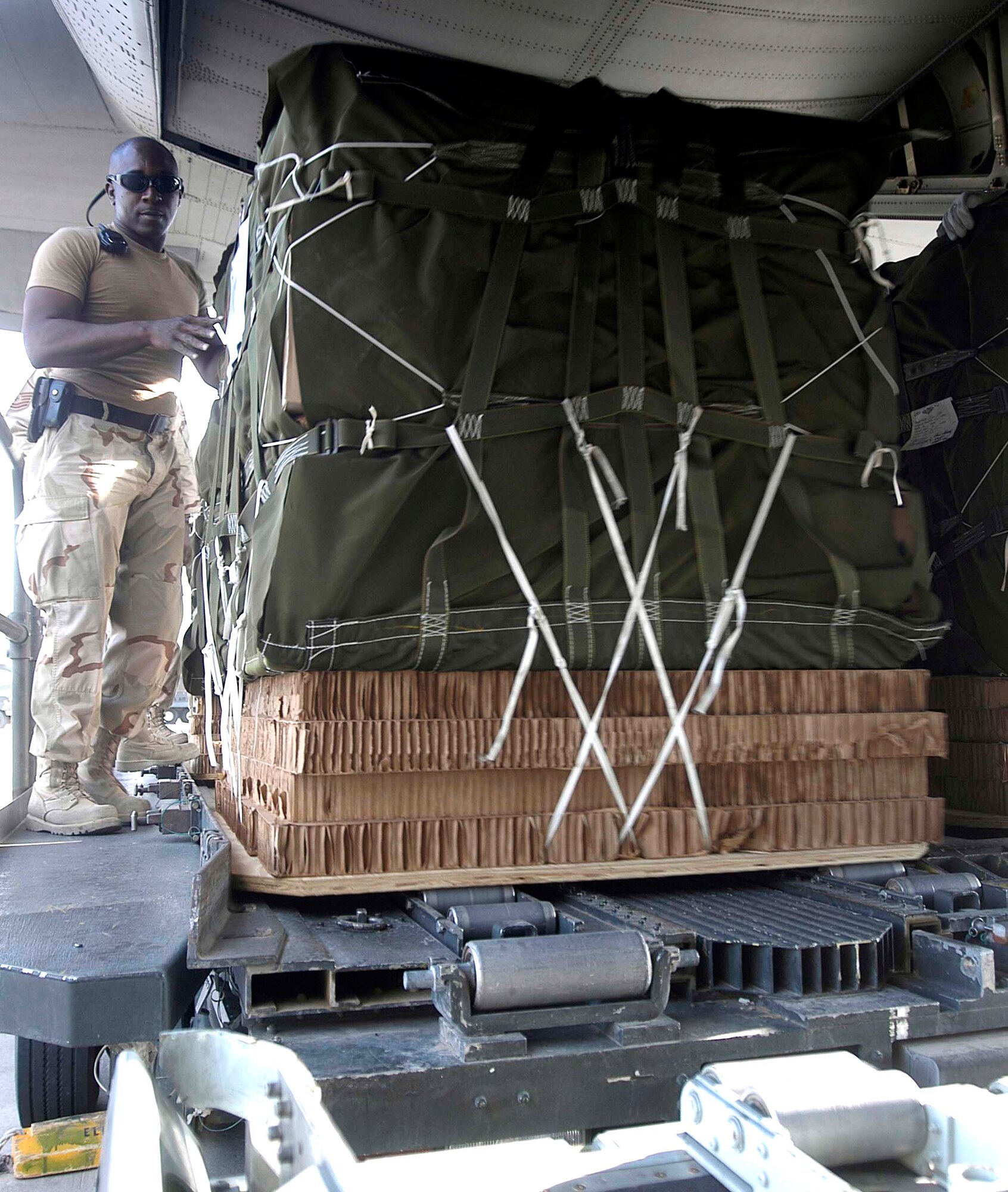 Staff Sgt. Anthony Redding loads a special container delivery system bundle on a C-130 Hercules on Tuesday, July 4, at Bagram Air Field, Afghanistan. Aircrews from the 774th Expeditionary Airlift Squadron dropped bundles of treats to Soldiers at forward operating bases throughout Afghanistan in honor of America's 230th birthday. The bundles contained items such as soda, beef jerky, CDs and DVDs requested by Soldiers to enhance morale. (US Air Force photo/Maj. David Kurle)