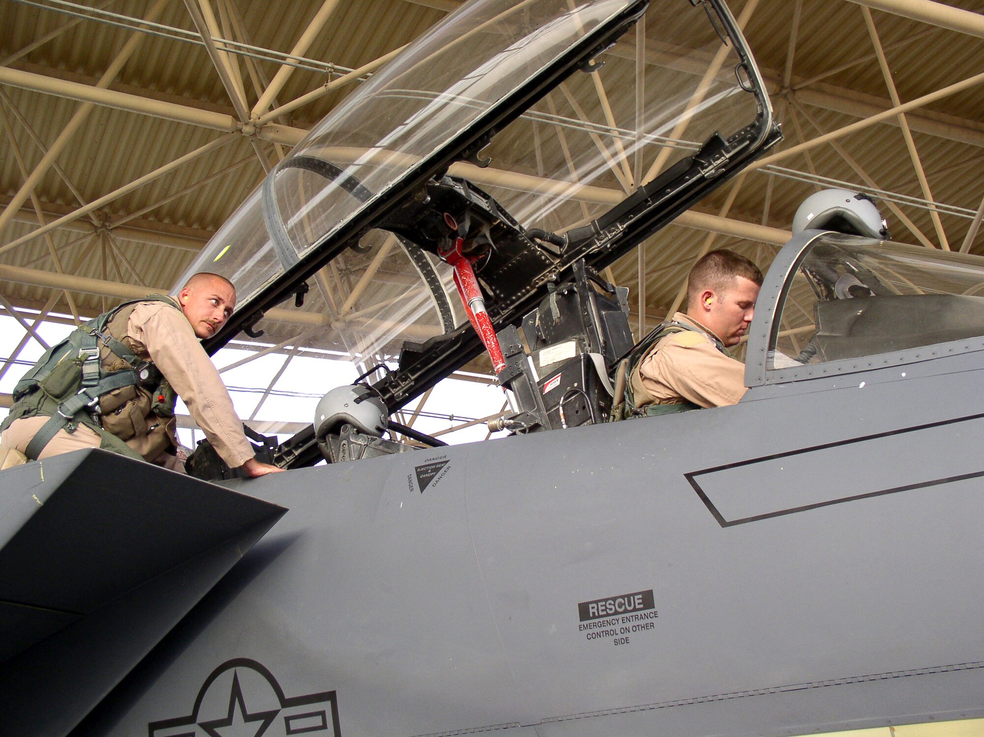 Capt. Michael Shields inspects the arming device on the ejection seat of an F-15 Eagle while Capt. Marc Johnson watches during a preflight inspection at a forward operating location in Southwest Asia on Sunday, July 2. The captains are deployed from the 335th Fighter Squadron at Seymour Johnson Air Force Base, N.C. Captain Shields is an F-15 Eagle weapons system officer and Captain Johnson is a pilot, both assigned to the 335th Expeditionary Fighter Squadron. (U.S. Air Force photo/Master Sgt. Dutch DeGroot)