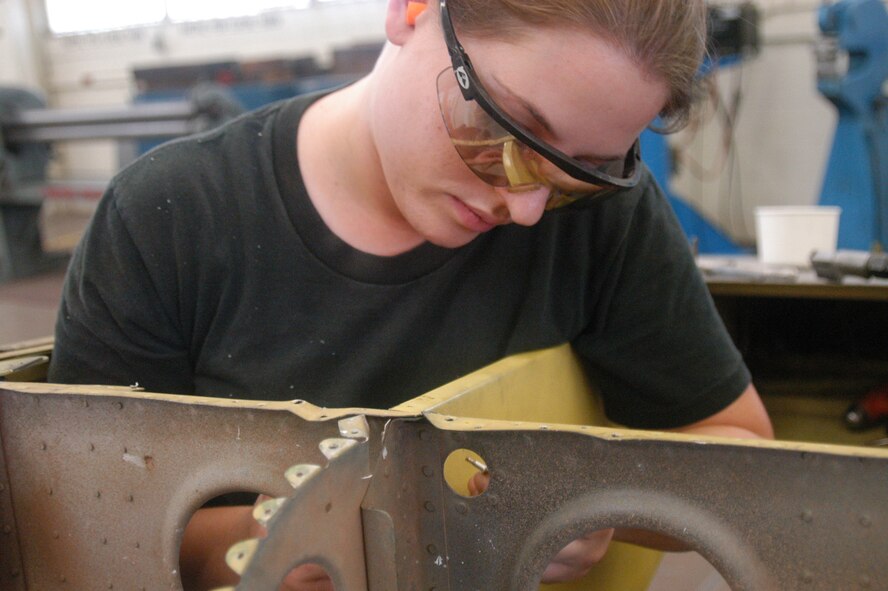Airman 1st Class Tiffany Waters, Aircraft Structural Maintenance, secures and strengthens a tail rudder with rivets.