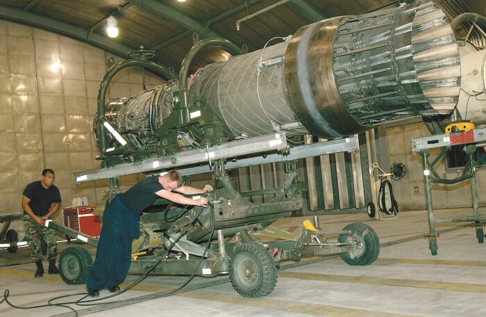 Staff Sgt. Carl Adee (right) and Staff Sgt. Randy James, 57th Component Maintenance Squadron aerospace propulsion mechanics, use a little elbow grease to align an engine trailer with the thrust bed in a Hush House at Nellis Air Force Base, Nev. The engine is one of two that powers the F-15E Strike Eagle. (U.S. Air Force Photo/Staff Sgt. Darryl Barnes)