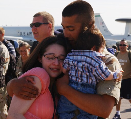 Senior Airmen Ruben Torres, 99th Civil Engineer Squadron firefighter, hugs his wife, Amanda, and their son upon returning to Nellis from deployment in Iraq May 13. About 50 Airmen returned after spending four months in support of Operation Iraqi Freedom. (U.S. Air Force Photo/Airman 1st Class Kasabyan Austin)