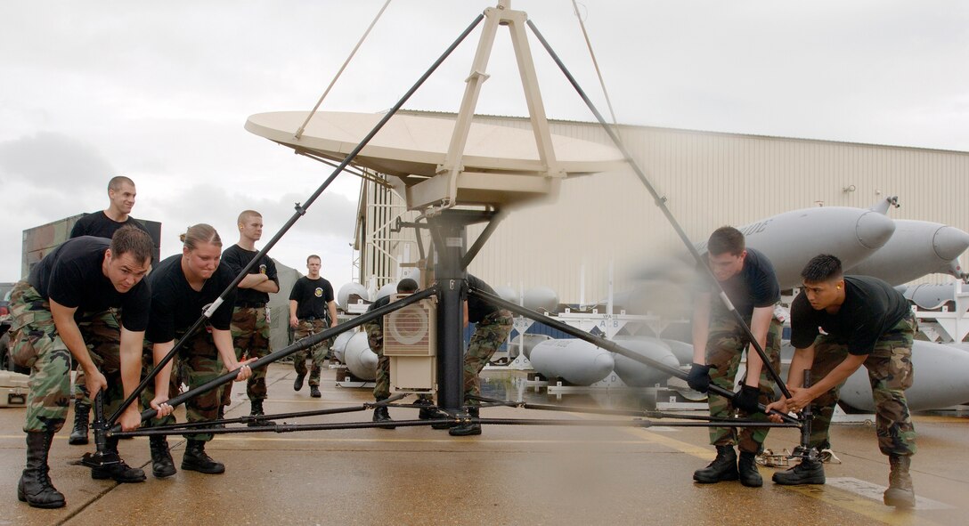 Members of the 1st Communications Squadron Theater Deployment Communications team at Langley Air Force Base, Va., lift and move a USC-60 satellite during a rain storm at Naval Air Station Oceana. The squadron is supporting the F-22 Raptors deployed to NAS Oceana during flightline construction at Langley. (U.S. Air Force photo/Staff Sgt. Eric T. Sheler) 