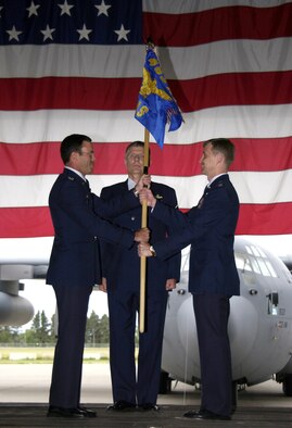 Col. John Gomez, left, passes the guidon to Lt. Col. Steven Hopkins while Master Sgt. Rick McKean observes during the 30th Airlift Squadron reactivation ceremony July 8 at the Wyoming Air National Guard base in Cheyenne.  The 30th AS is the first active duty air mobility squadron to report to an Air National Guard wing.  Colonel Gomez is the 463rd Airlift Group commander from Little Rock Air Force Base, Ark.  Sergeant McKean is also from the 463rd.  Colonel Hopkins is the 30th AS commander.  (U.S. Air Force photo/Tech. Sgt. Kimberly Spinner)