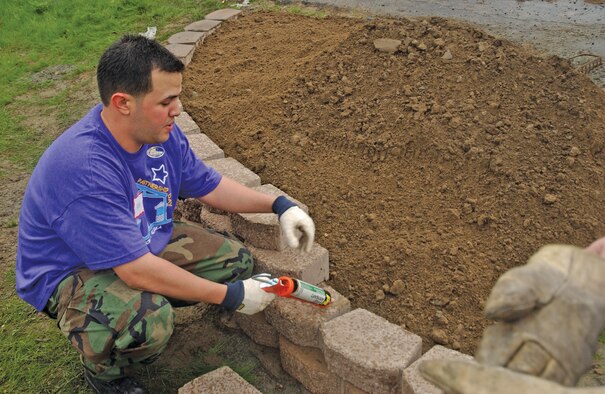 EIELSON AIR FORCE BASE, Alaska--Senior Airman Eddie Caro, 354th Fighter Wing command chief executive assistant, lays brick on one of seven planters constructed during Community Partnership Day. Military and civilian volunteers worked through day-long inclement weather to accomplish twice their projected goal. (U.S. Air Force photo by Airman Christopher Griffin)