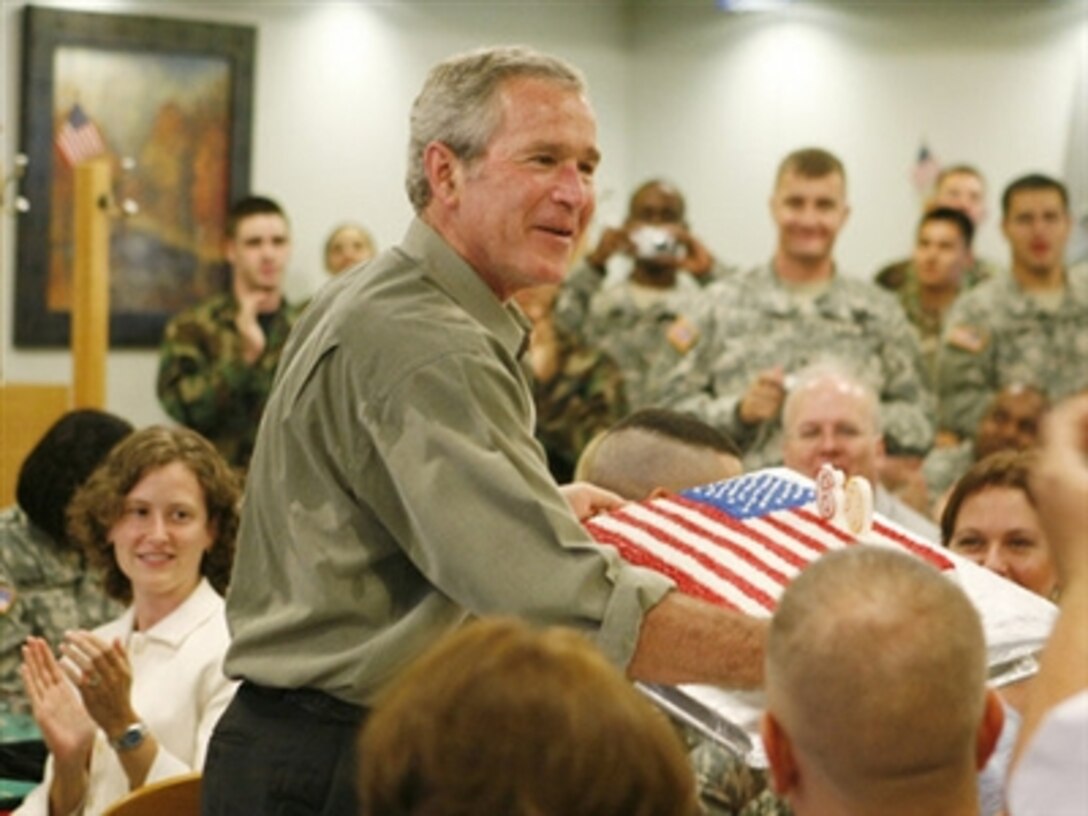 President George W. Bush holds a birthday cake in honor of his upcoming 60th birthday, at a luncheon with troops at Fort Bragg, N.C., July 4, 2006. Bush earlier addressed the troops at an Independence Day celebration thanking them for their service to the nation. 
