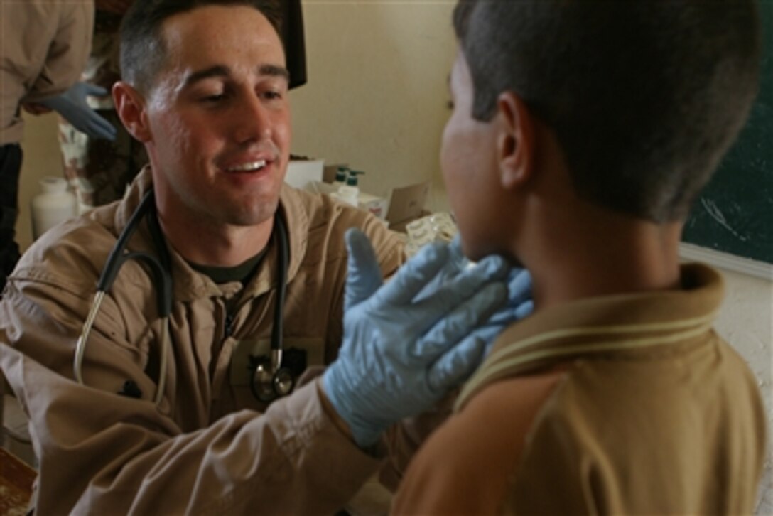 A U.S. Navy corpsman with the 1st Battalion, 1st Marine Regiment, Regimental Combat Team 5 examines a child's throat during a combined medical operation conducted with Iraqi army soldiers at a schoolhouse in Fallujah, Iraq, on June 29, 2006.