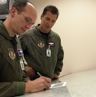 Maj. Nathan Tracy looks on as Maj. Pat Menaire, both C-130 aircrew students at Little Rock Air Force Base, Ark., points out a route during their flight planning training at the 714th Training Squadron.