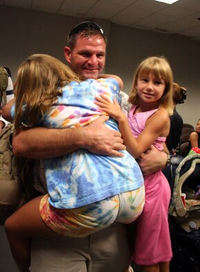 Capt. Paul Lorenz, 20th Special Operations Squadron MH-53 PAVE LOW pilot, hugs his daughters upon his return home from a deployment July 4. Several squadrons from Hurlburt Field had servicemembers come back on Independence Day.  (U.S. Air Force Photograph by Jamie Haig)
